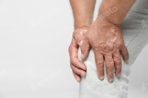 Preview: Senior man having knee problems on grey background, closeup. Space for text