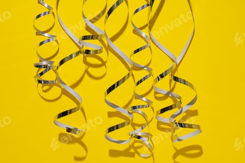 Preview: Silver swirling ribbons on yellow background, close up