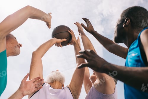 Preview: low angle view of interracial elderly sportsmen playing basketball together