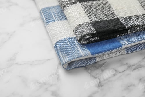 Preview: Folded colorful kitchen towels on marble table, closeup view. Space for text