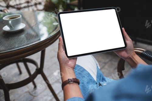Preview: Mockup image of a woman holding digital tablet with blank white desktop screen in the outdoors cafe