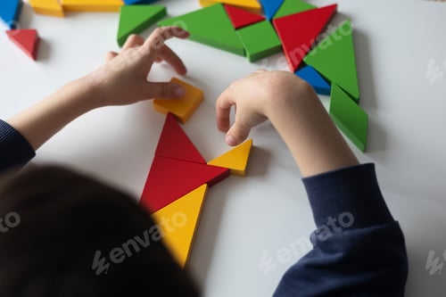 Preview: Kid composing a puzzle with colorful wooden geometric shapes
