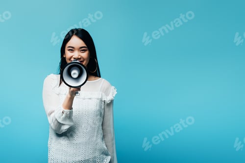 Preview: smiling brunette asian woman holding loudspeaker on blue background