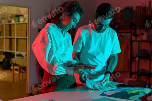 Preview: Couple of designers look through textile samples. Self-employed tailor and seamstress in workshop
