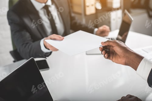 Preview: Take It. Close Up Of Hand Of African Businessman Is Sitting At Table And Holding Sheet Of Paper