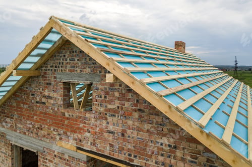 Preview: Aerial view of a brick house with wooden roof frame under construction