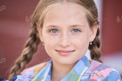 Preview: Caucasian young girl with braided hair smiling in colorful plaid shirt