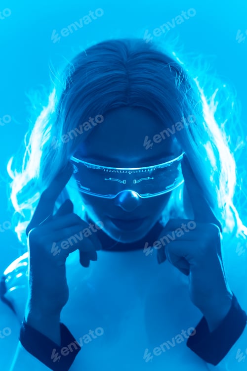 Preview: A woman in a futuristic suit and glasses with blue lights, virtual metaverse concept, serious look