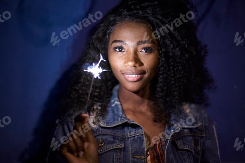 Preview: Portrait of smiling young woman with sparkler