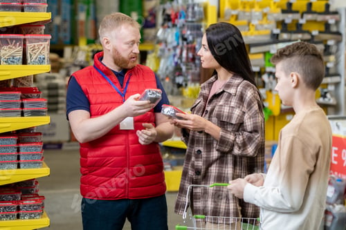 Preview: Bearded worker of hardware store consulting young woman