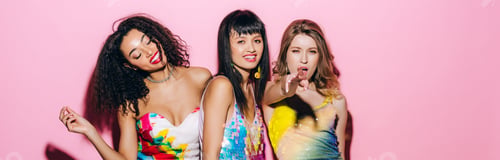 Preview: panoramic shot of emotional fashionable multiethnic girlfriends dancing on pink
