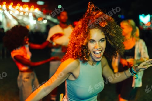 Preview: Young woman dancing and enjoying music festival at night