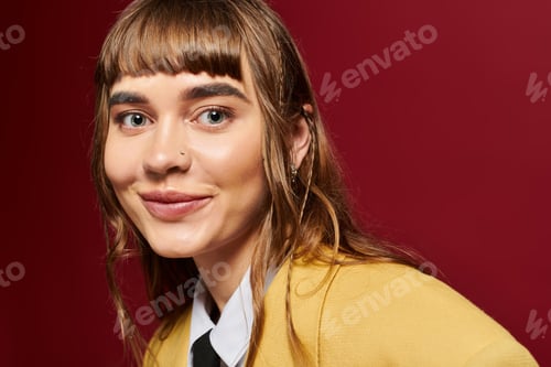 Vista previa: Bright smile of a young female student against a vibrant red backdrop showcasing her joy in studying