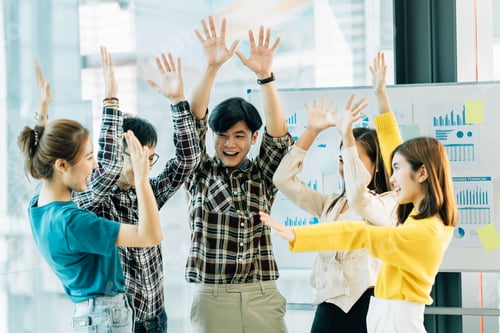 Preview: Happy successful asian business team giving a high fives gesture as they laugh and cheer thei