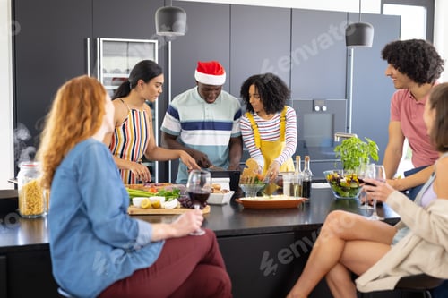 Preview: Happy diverse friends with santa hat cooking at christmas