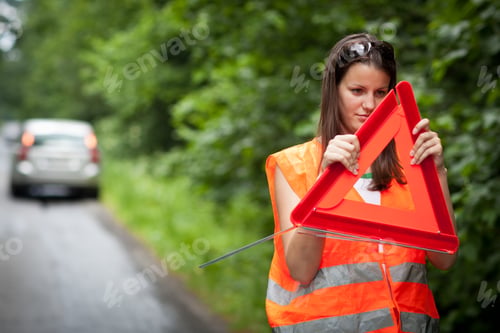 Preview: Young female driver wearing a high visibility vest, calling the