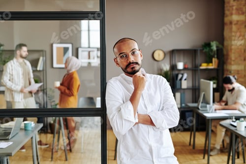 Preview: Young entrepreneur in white shirt standing against his colleagues