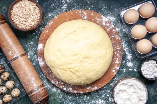 Preview: top view raw dough with white flour and eggs on dark-blue background pastry bake cake pie raw fresh