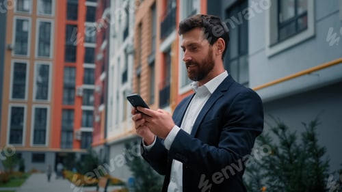 Apuesto y exitoso hombre de negocios caucásico se encuentra cerca de un moderno edificio residencial en la ciudad trabajando