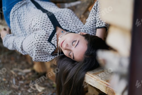 Preview: Beautiful shot of a young brunette female lying on a wooden bench