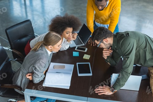 Preview: high angle view of multicultural businesspeople looking at tablet in office