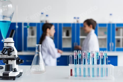 Preview: selective focus of test tubes and microscope near children on blurred background in chemical lab
