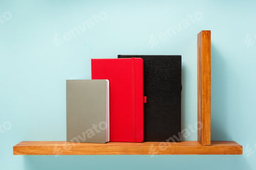 Preview: notepad and book on shelf at wall background