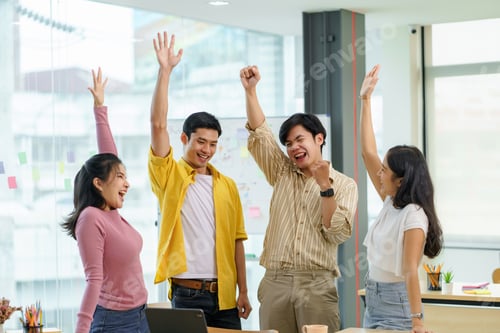 Preview: Happy group of young Asian business people in casual wear successful excited raised hands rejoicing.