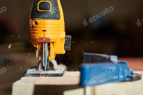 Preview: close-up of sawing a wooden board by laser guidance with an electric jigsaw. with flying sawdust to