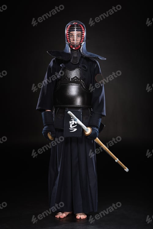 Preview: Full length view of kendo fighter in armor holding bamboo sword on black
