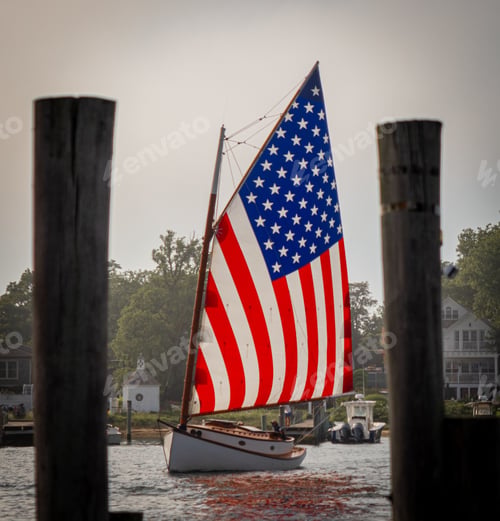 Preview: Catboat with an American Flag sail in a harbor