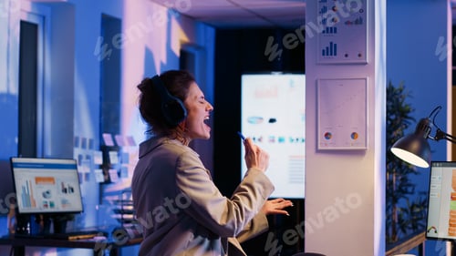 Preview: Business woman working at night listening to music