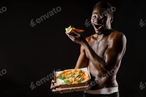 Preview: Naked African enjoying two pizza slices. Hot food delivery model