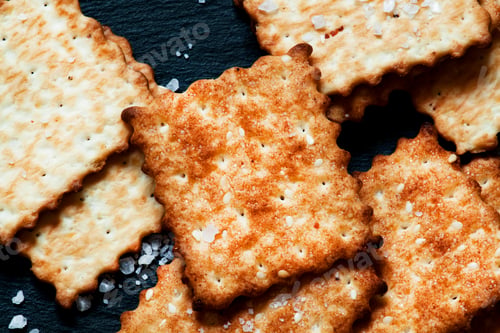 Preview: Crispy golden crackers with salt on dark stone background, top view
