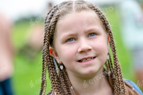 Preview: A smiling young girl with braided hair and a green background.