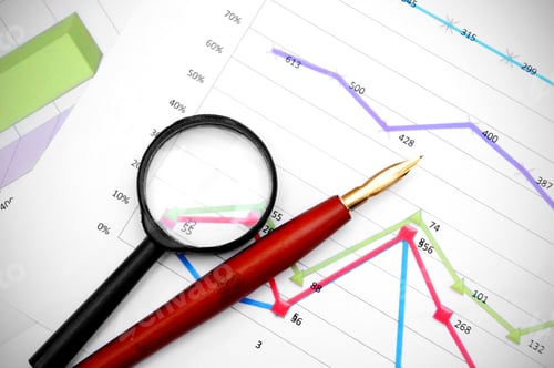 Preview: Magnifier and pen on financial graphs.