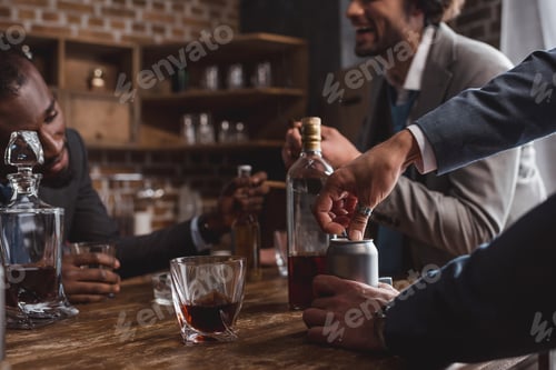 Preview: cropped shot of multiethnic men in suits drinking alcoholic beverages together