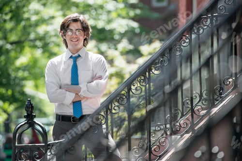 Preview: City life. Businessman standing with arms folded outside a townhouse, on the steps.