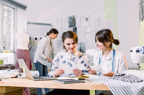 Preview: Two attractive women dressmakers designers choosing trendy sketches
