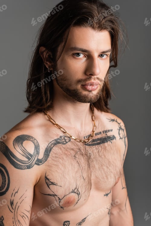 Preview: Portrait of shirtless and tattooed model looking at camera isolated on grey