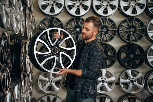 Preview: Brand new disk. Man worker is maintenance station with tires, wheels