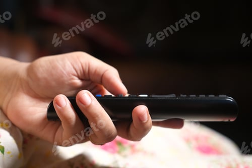 Preview: close up of women hand holding tv remote.