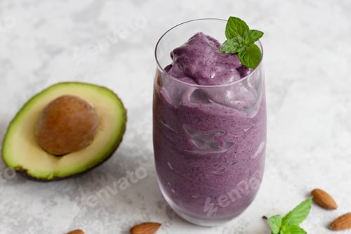 Purple Smoothie Garnished with Mint next to Avocado