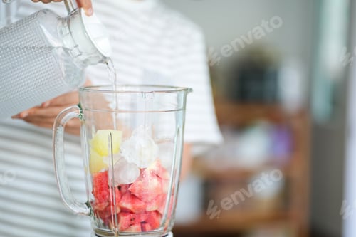 Preview: close up of woman with blender making fruit shake at home