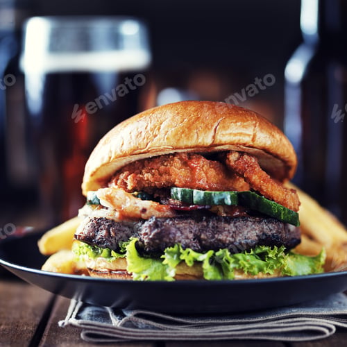 Preview: big hamburger with beer and onion rings served with fries