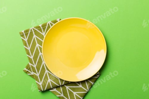 Preview: Top view on colored background empty round yellow plate on tablecloth for food.
