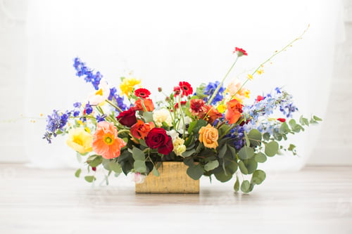 Preview: Horizontal shot of a bouquet full of different colored flowers in a square basket