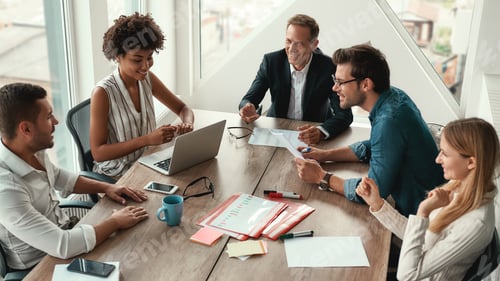Preview: Sharing new ideas. Group of young business people discussing something and smiling while sitting at