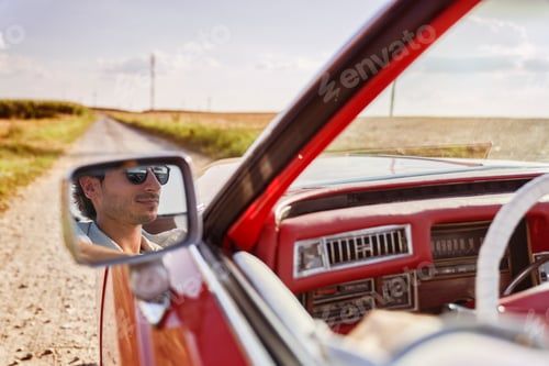 Preview: Man driving red convertible on a dirt road