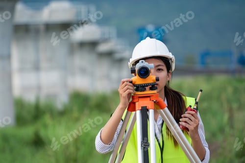 Preview: Construction workers wearing a safety vest and a hard hat is holding a surveying instrument